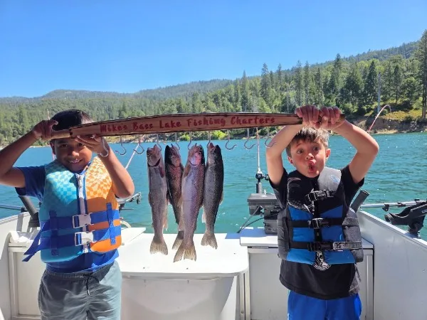 Young anglers proudly showing off their fresh trout catch on Bass Lake