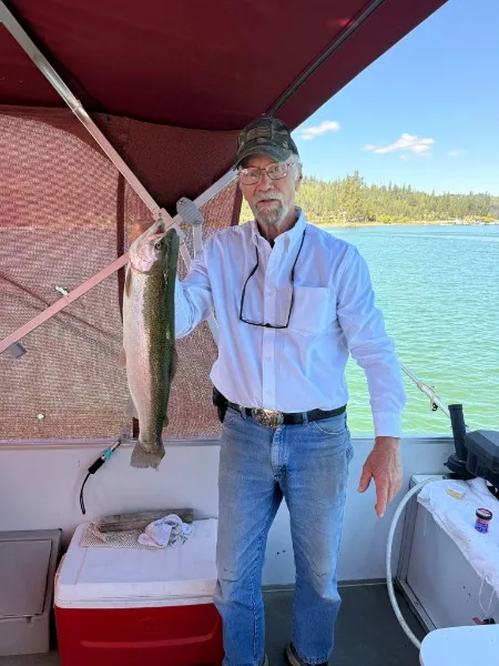 Mike Beighey holding a trophy rainbow trout on the boat